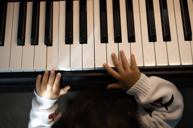Imágen de manos infantiles encima de un teclado de piano